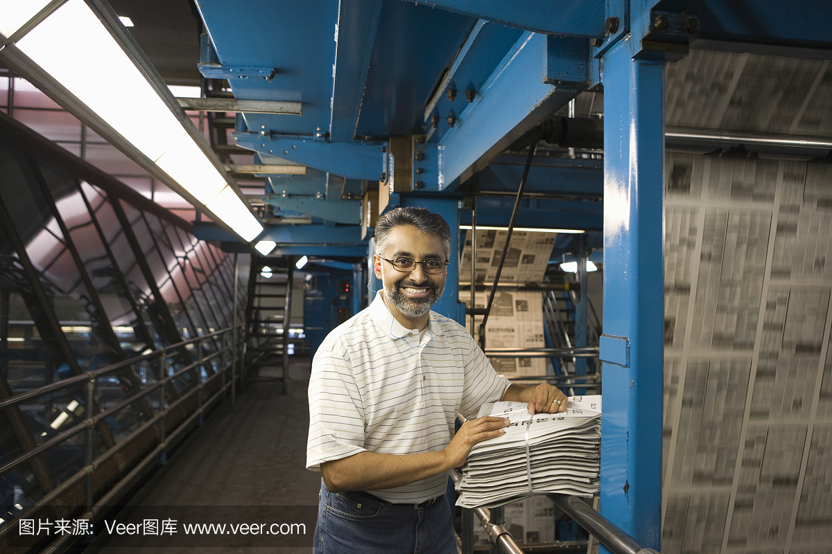 工厂里拿着报纸微笑的男人
